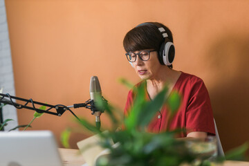 Middle-aged female radio presenter talking into the microphone and reading news - radio broadcast...