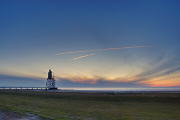 Fototapeta premium sunset at a lighthouse at low tide at north sea coast