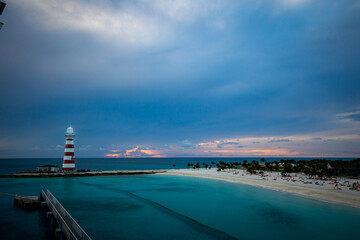 A sunset over idilic travel destination with a beach next to lighthouse