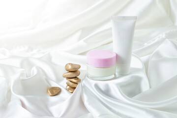 Fototapeta na wymiar Beauty products mockup on a stand or podium pedestal , luxury advertising display. White creamy satin background with zen stones
