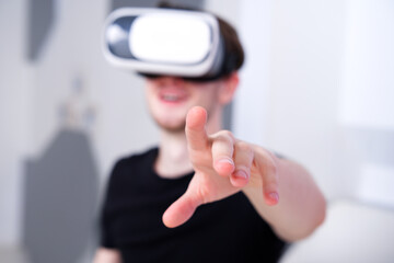 Portrait of happy young handsome man, positive smiling guy using, wearing a modern device virtual reality headset mask or 3D, AR, VR glasses, playing the game. People and technology metaverse concept