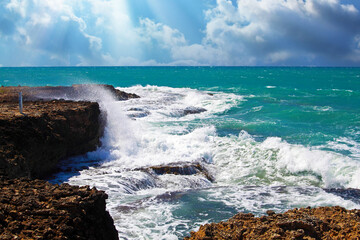 Beautiful caribbean coastal landscape with splashing waves, rough rocky coastline, storm clouds, sun rays - Treasure Beach, Jamaica