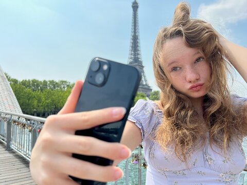 a girl makes a selfie against the backdrop of the Eiffel Tower build a face smiles she is very beautiful. High quality photo