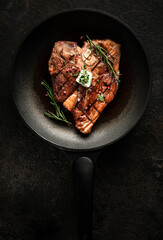 Grilled t-bone steak with seasonings, rosemary and butter in a grill pan. Cooking porterhouse beef...