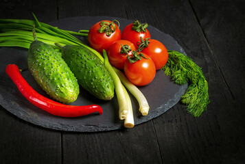 Set for fresh vegetable salad. Red tomatoes and green young onions with cucumber on a plate