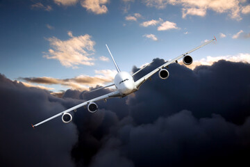 Passenger plane in flight. Aircraft with left heeling flies high in the blue sky through the dark clouds. Front view of airplane.