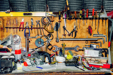 Workshop with tools. A collection of various repair tools hanging on the wall above the desktop.