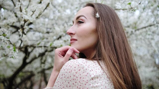 Portrait of young beautiful ukrainian brunette woman in the flowered garden in the spring time