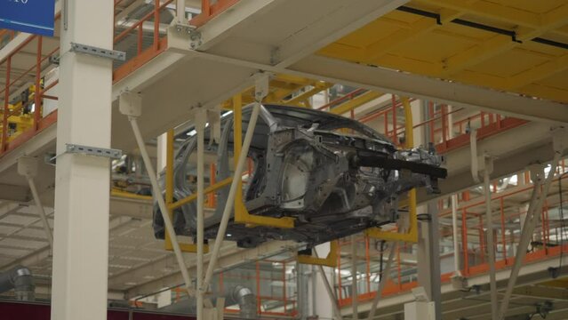 The car frame moves along the conveyor belt.