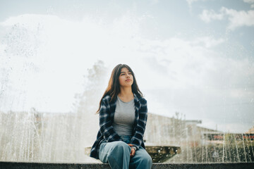 Retrato de mujer contenta sentada al borde de una pileta en un parque. Concepto de Personas.