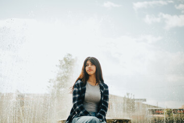 Retrato de mujer contenta sentada al borde de una pileta en un parque. Concepto de Personas.