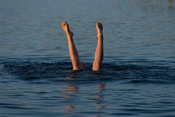 A person standing upside down in a lake. Legs visible over water..