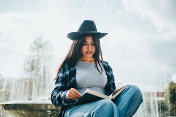 mujer sentada al costado de una pileta leyendo un libro. Concepto de personas y estilos de vida.