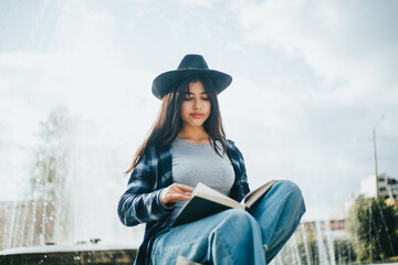 mujer sentada al costado de una pileta leyendo un libro. Concepto de personas y estilos de vida.