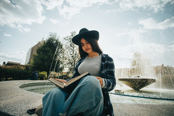 mujer sentada al costado de una pileta leyendo un libro. Concepto de personas y estilos de vida.