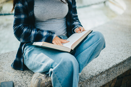 Manos de mujer pasando paginas de un libro sentada en un parque. Concepto de Estilo de Vida.