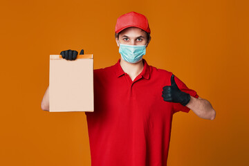 Fototapeta na wymiar Delivery man employee in red cap face mask, empty cardboard box