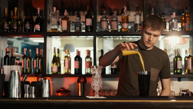 A professional bartender is preparing an alcoholic cocktail with ice cubes to customers at the bar or disco club,Sex on the beach cocktail.