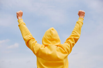 A man in a bright yellow hoodie is happy and happy against a light background. A stylish concept of...