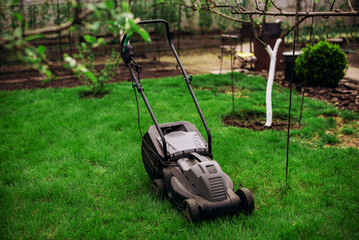Lawn mower on green lawn in the garden