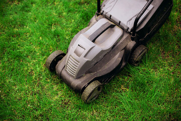 Lawn mower on green lawn in the garden