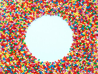 Colored sugar balls on a white background in the form of a round frame. Used to decorate pastries and sweets. Place for text