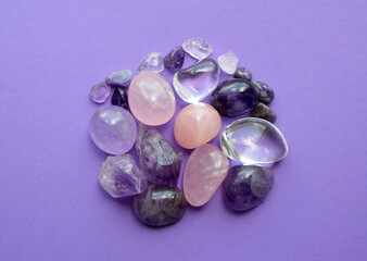 Gemstone minerals on a purple background. Round tumbling minerals of amethyst and amethyst crystal.