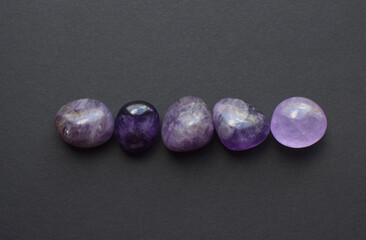 Gemstone minerals on a black background. Round tumbling minerals of amethyst and amethyst crystal.
