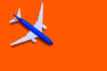 Airplane model on a orange background with free space for text or advertising. Tourism or freight transport concept. Toy airplane on a yellow background with a top view