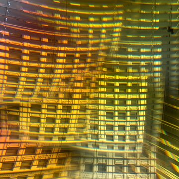 Colorful abstract pattern created with prism in front of camera lens. Facade of a historic building seen as multiple composited images through window with Venetian blinds