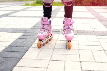 The girl rides on pink roller skates with a view of her legs. Part of the body in the form of legs...