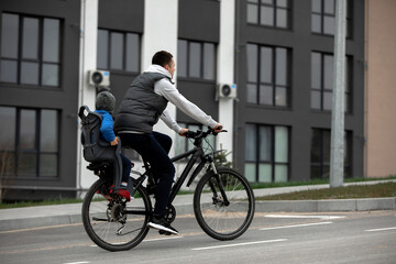 Fototapeta premium father riding bike with son in bike seat