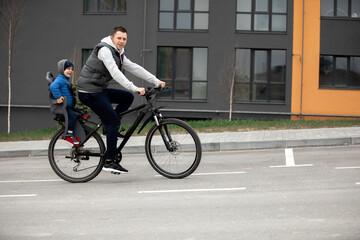 Fototapeta na wymiar father riding bike with son in bike seat