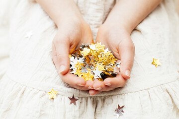 Close-up of gold and silver stars in children's hands. Party, new year celebration. The concept of children's creative creativity