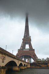 Obraz premium Eiffel Tower view from a rainy day, top of the tower is veiled with rainy clouds