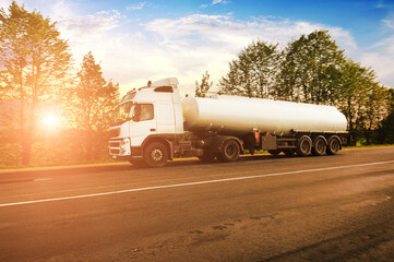 Tanker truck with space for text on a road against a sky with a sunset
