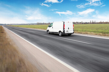 White van on a countryside road in motion against a sky with clouds