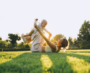 Young mother and baby playing in park at summer. Beautiful mom and child outdoors. Parent with kid...