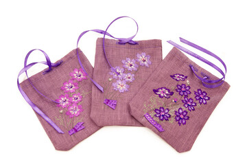 Three decorative linen bags with embroidery. Purple linen pouch with embroidered flowers, storage pouch for small items, for dried herbs, aromatic pouch, interior detail. Isolated on white background