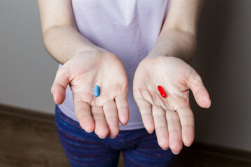 Red and blue pills in woman hands.