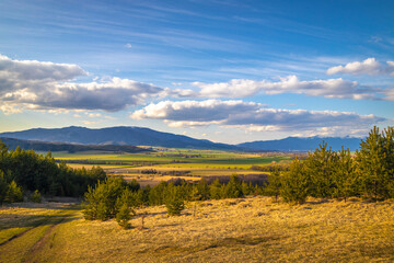 Naklejka na ściany i meble Sunny spring rural landscape, valley of fields and meadows with mountains in the background. Turiec Valley in Slovakia, Europe.