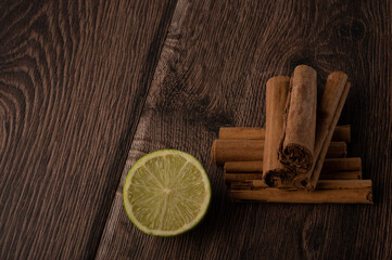 Lime and cinnamon on a dark wood background with copy space