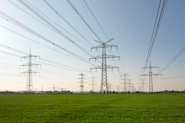 A lot of high-voltage power line, transmission tower overhead line masts, high voltage pylons also known as power pylons on the fields with grain. 