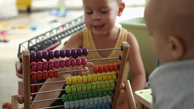 two little toddlers baby boys brothers playing together with toys on floor at home. brother not let elder sibling play, elder one trying to get away. colorful abacus, xylophone. children communication