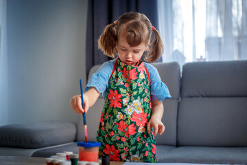 Adorable little girl painting with gouache at home, in kindergaten or preschool - 502482524