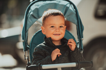Sweet baby boy in a stroller bicycle outdoors. Little child in a pram. Infant kid in a pushchair. Spring walks with kids.
