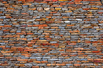 Full frame close up, stone wall background, multi-colored interlocking bricks