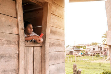 Mestizo woman inside her wooden house in a rural community in the Caribbean of Nicaragua using her...