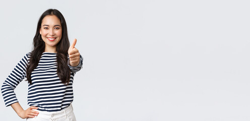 Lifestyle, beauty and fashion, people emotions concept. Cheerful cute asian girl thumb-up in...