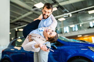 Beautiful young happy couple holding a key of their new car.